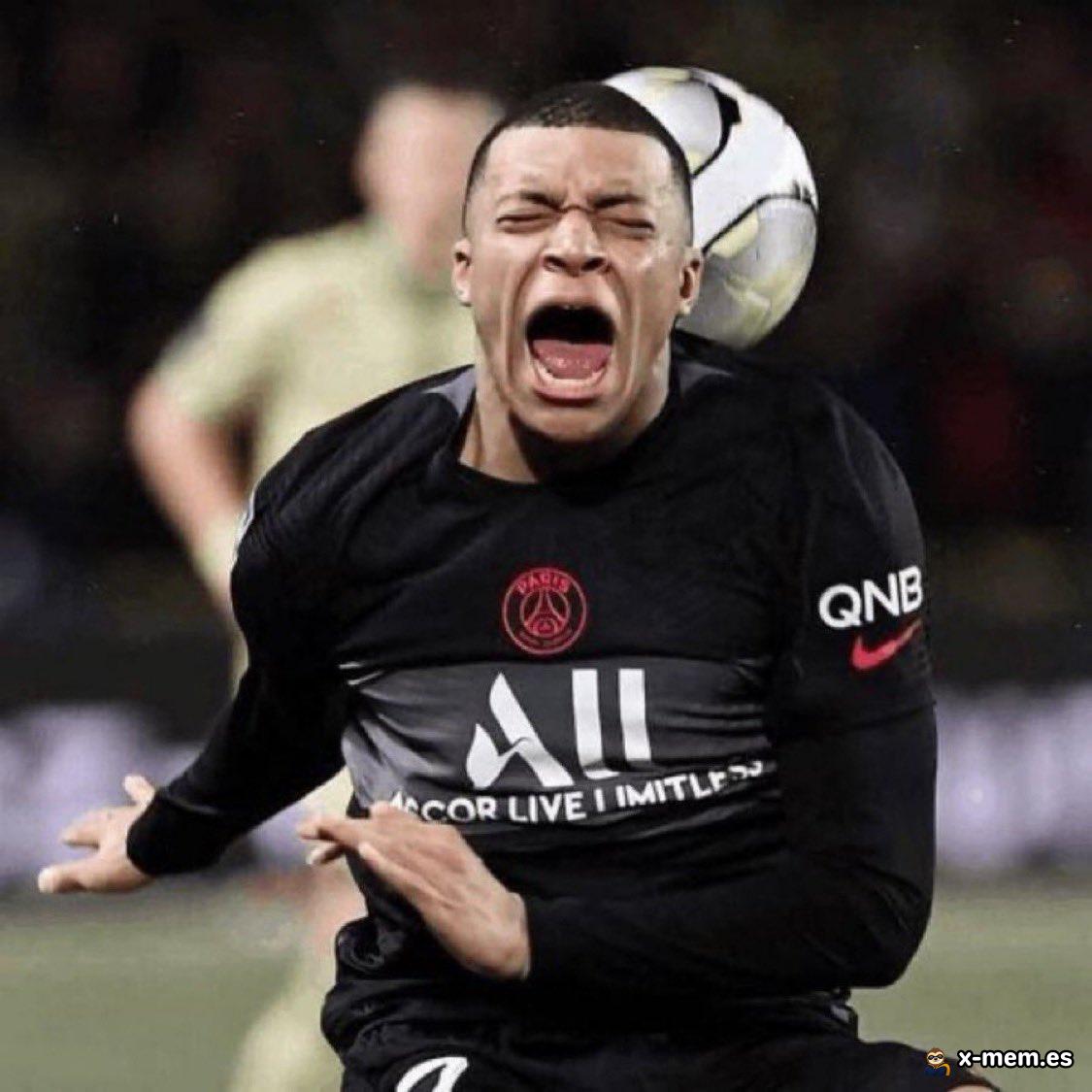 Kylian Mbappé grimace en hurlant sur le terrain au moment où un ballon de football lui frappe l’arrière de la tête.