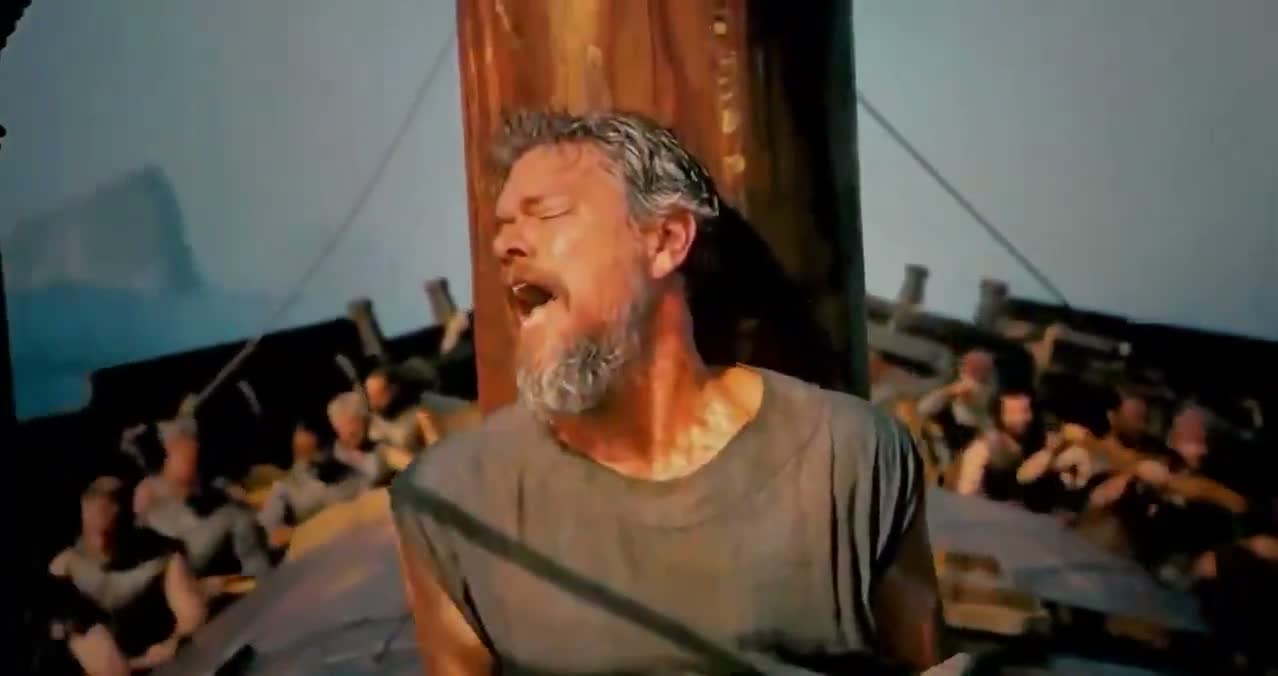 Matt Damon en Ulysse crie attaché au mât d’un navire dans L’Odyssée, pendant que les rameurs luttent autour de lui.