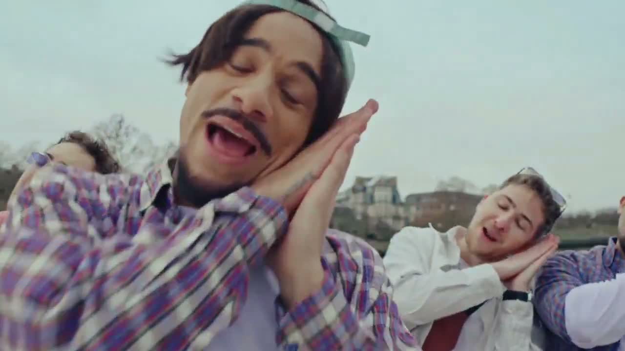 Mister V chante joyeusement en groupe sur une terrasse en extérieur.